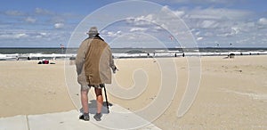 Old man looks out to sea on a beach