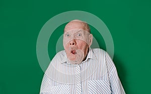 an old man makes faces at an isolated green background. chromakey