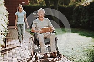 Old Man and Nurse Walk Together. Aged and Stroller