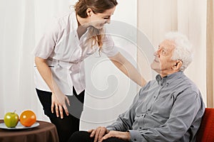 Old man in nursing home with helpful carer