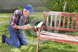 Old man painting bench in garden