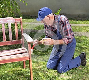 Old man painting bench in garden