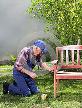 Old man painting bench in garden