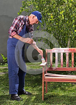 Old man painting bench in garden