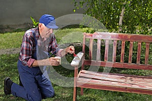 Old man painting bench in garden