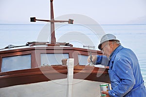 Old man painting boat