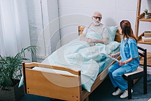 Old man patient and nurse discussing news