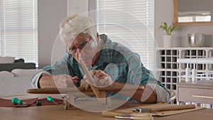 Old man perfecting a handmade wooden plane