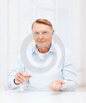 Old man with pills ang glass of water