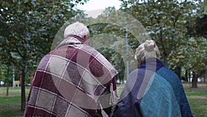 Old man in plaid walking with his wife with walking stick along park, care home