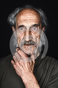 Old man with a plam on the chin loking at the camera with scared expression