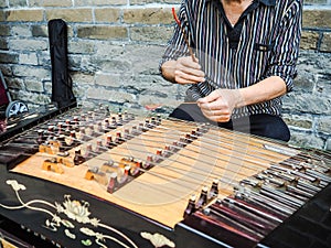 Old man playing with bamboo hammers on a yangqin