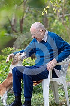 Old man playing with dog in garden