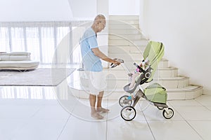 Old man playing with his grandchild in a stroller