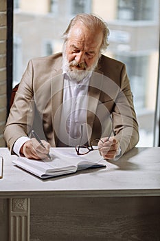 Old man pleasant man is writing his ideas in the notebook