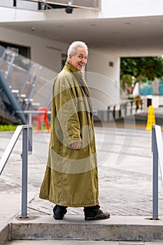Old man posing in a green oversize trenchcoat photo