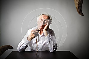 Old man is praying with rosary beads. Prayer and temptation.