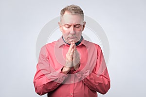 Old man put hands together in prayer or meditation