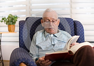 Old man reading book at home