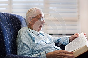 Old man reading book at home