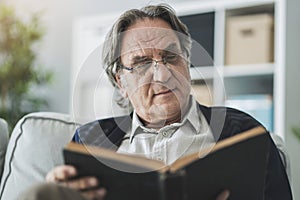 Old man reading book at home