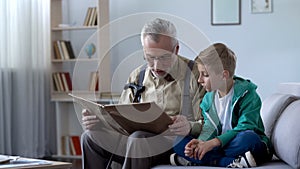 Old man reading book to grandson, giving experience to younger generation