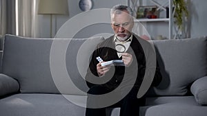 Old man reading instruction for pills with magnifier, treating vision impairment