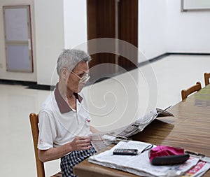 Old man reading newspaper in library
