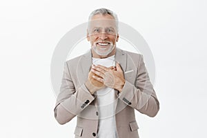 Old man receiving heartwarming and touching gift pleased and delighted smiling with crooked teeth at camera holding