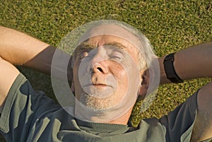 Old man relaxing in the sun on grass