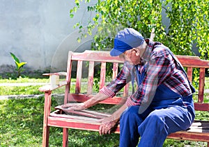 Old man repairing bench in garden