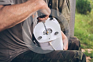 Old man repairs retro juicer in fresh air