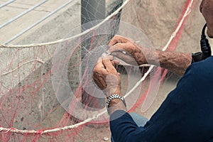Old man reparing fishing net