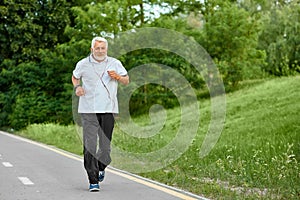 Old man running on modern city park`s racetrack.