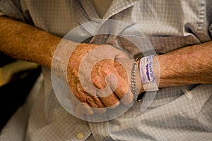 Old man's hands with hospital wristband