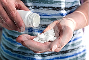 The old man`s hands are pouring pills from a white bottle into his hand. Medical concept. Close-up