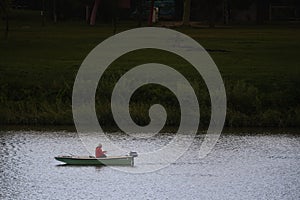 Old man, senior male relaxed and fishing on the Tisza river on a small rowing boat