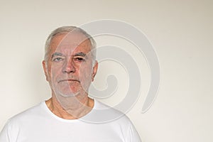 Old man senior  white t shirt closeup next to the wall healthy unhappy frown sad angry