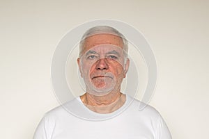 Old man senior  white t shirt closeup next to the wall healthy unhappy frown sad angry