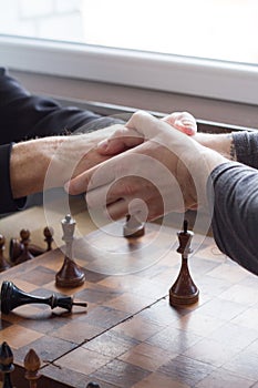An old man shakes hands with an opponent in a game of chess, he lost and acknowledges it