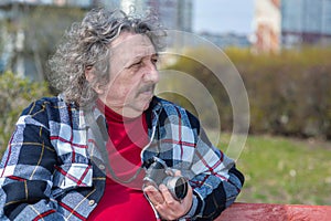 Old man sits on bench. Elderly guy is smiling. He deserves a good rest. All problems left behind
