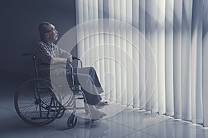 Old man sits on wheelchair while daydreaming