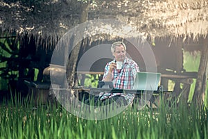 Old man sitting at a desk on a outdoor using a laptop