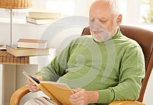 Old man sitting at home reading