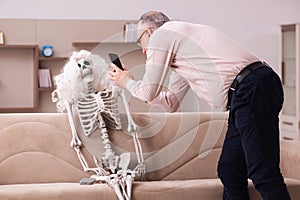 Old man sitting on the sofa with the female skeleton