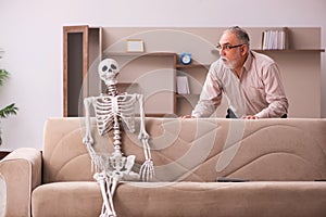 Old man sitting on the sofa with the female skeleton