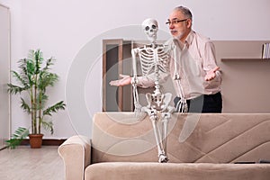 Old man sitting on the sofa with the female skeleton