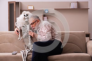 Old man sitting on the sofa with the female skeleton