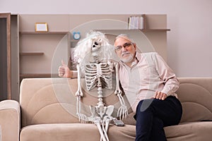 Old man sitting on the sofa with the female skeleton