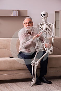 Old man sitting on the sofa with the female skeleton